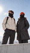 Un homme et une femme sur un toit en hiver, cache-cou et cagoule noirs