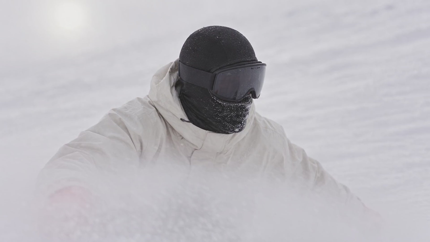 Snowboardeur en cagoule dans la neige soulevée
