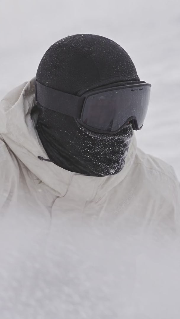 Snowboardeur en cagoule dans la neige soulevée
